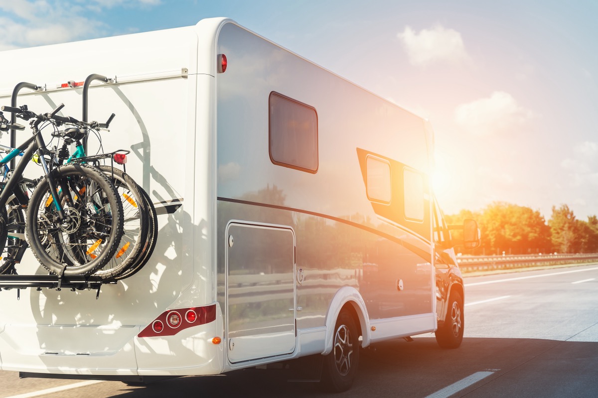 Weißes Wohnmobil mit Fahrradträger auf der Autobahn im Abendlicht